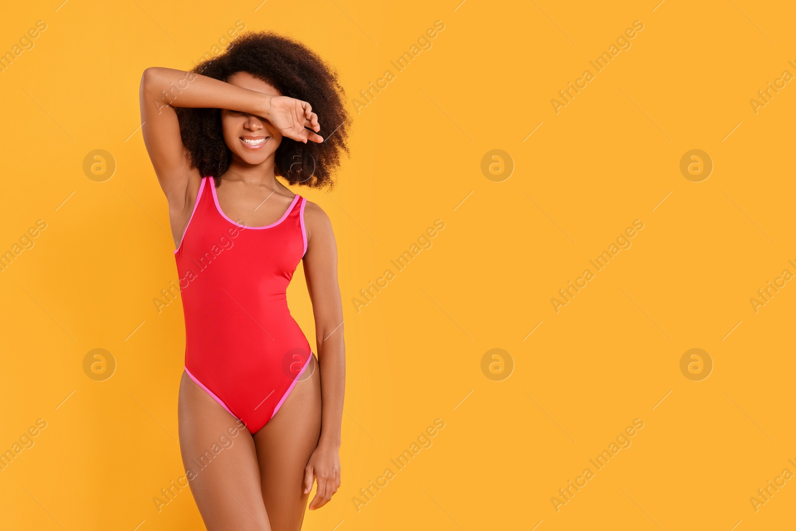 Photo of Beautiful woman in bright one-piece summer swimsuit on yellow background, space for text