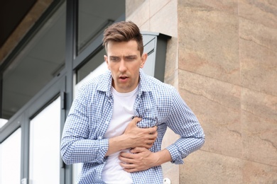 Photo of Young man having chest pain outdoors. Heart attack