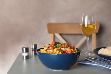 Photo of Bowl with delicious rice pilaf served on table against color background