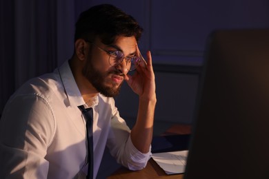 Photo of Tired young man working late in office