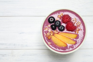 Delicious acai smoothie with peach slices and oatmeal on white wooden table, top view. Space for text