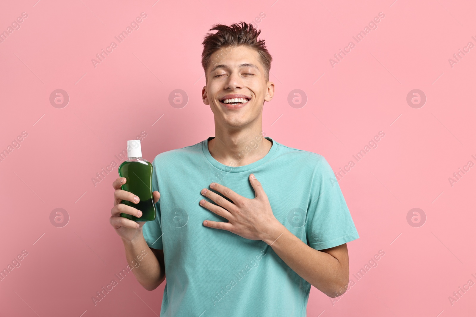 Photo of Young man with mouthwash on pink background