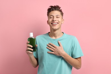 Photo of Young man with mouthwash on pink background