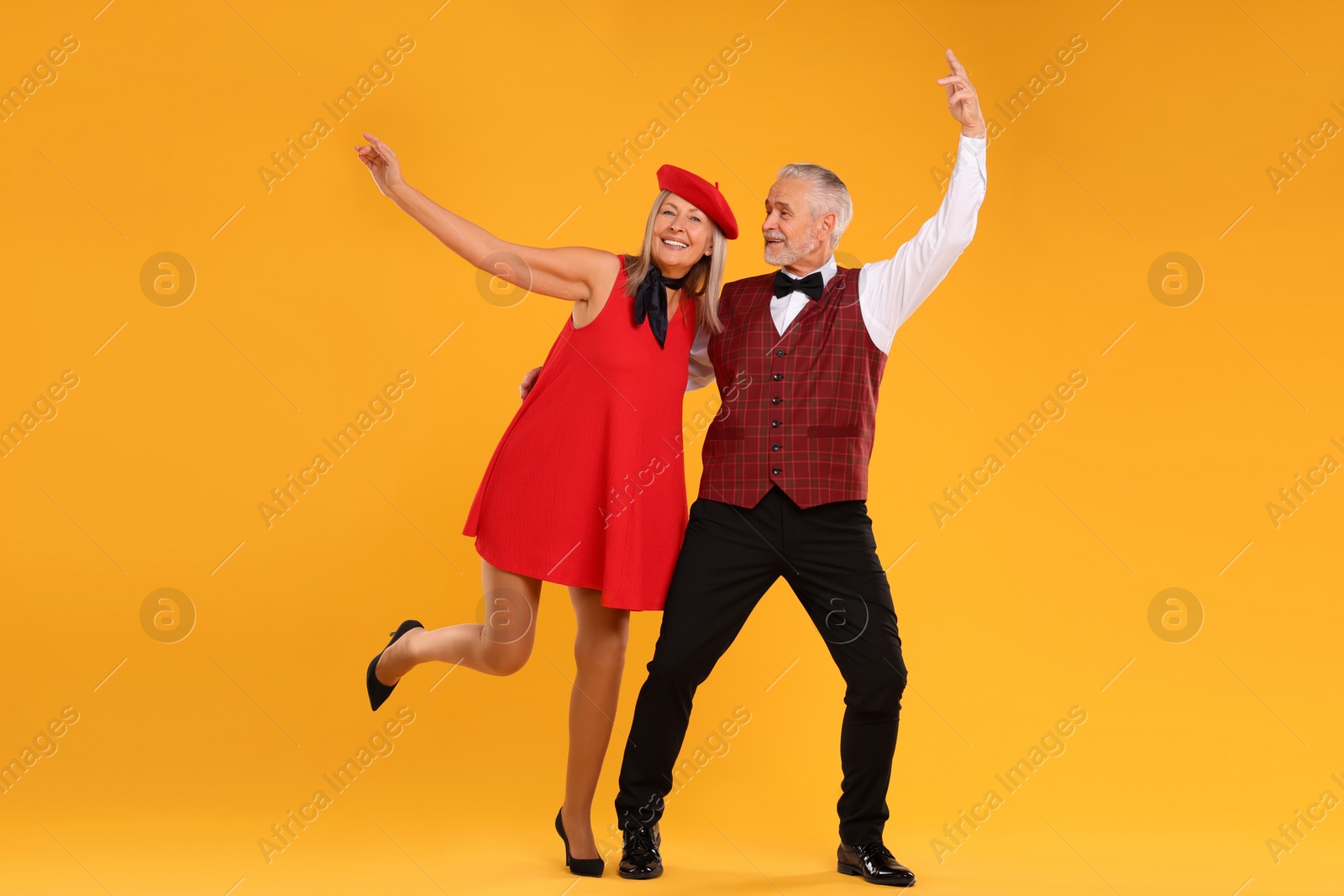 Photo of Senior couple dancing together on orange background