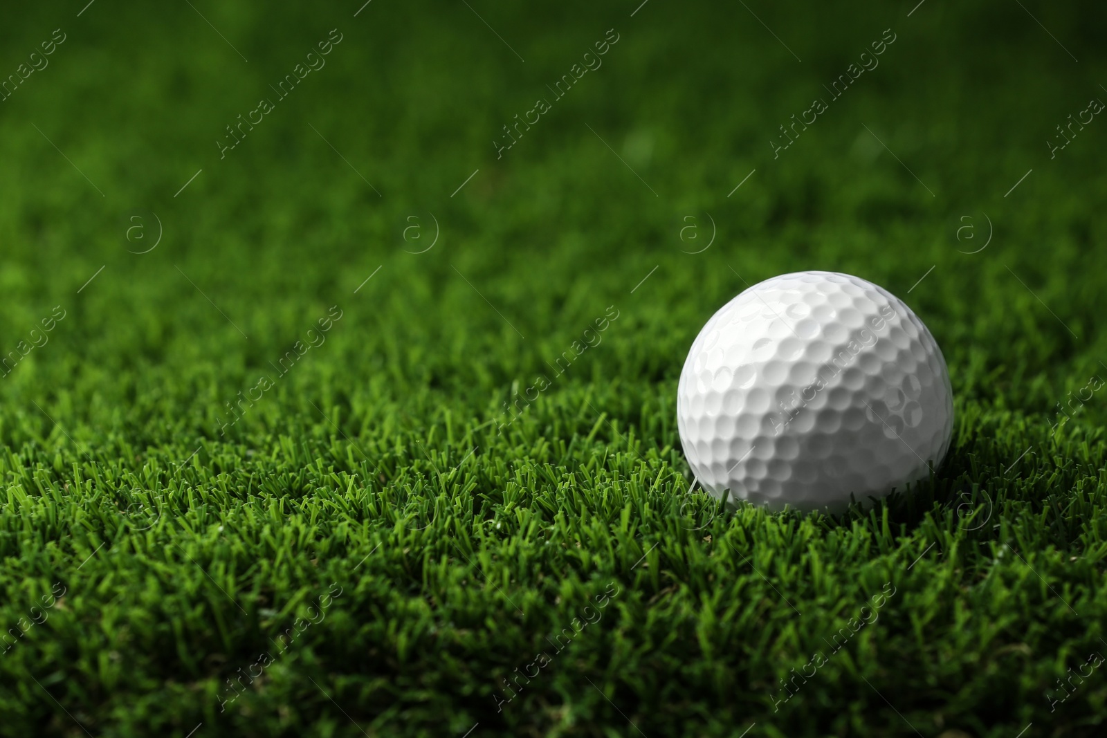 Photo of Golf ball on artificial grass, space for text