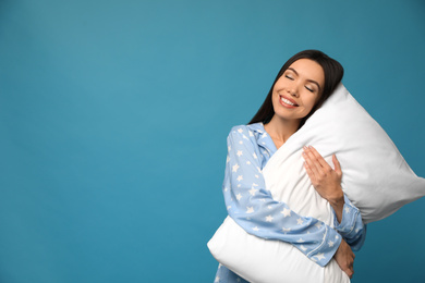 Photo of Beautiful Asian woman with pillow on blue background, space for text. Bedtime