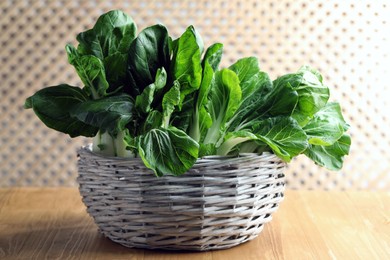 Photo of Fresh green pak choy cabbages in wicker basket on wooden table