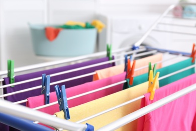 Clean laundry hanging on drying rack indoors, closeup