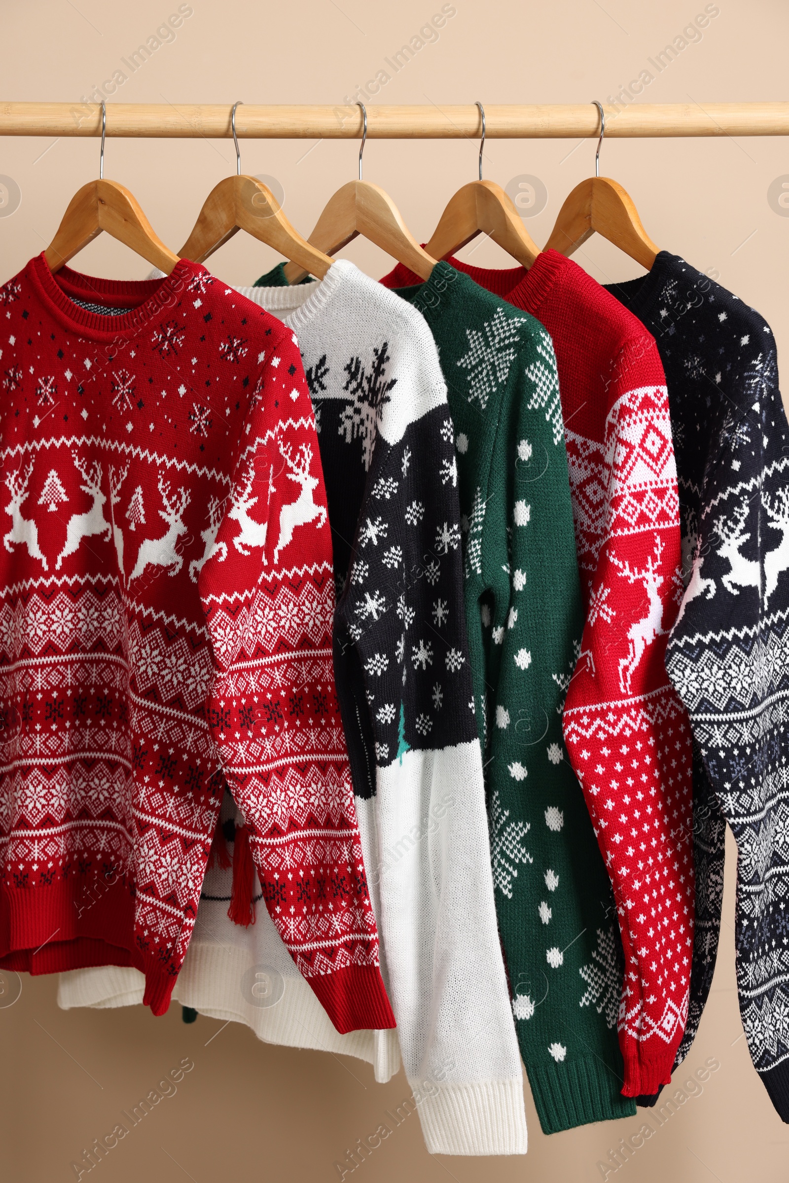 Photo of Rack with different Christmas sweaters on beige background