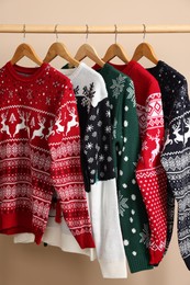 Rack with different Christmas sweaters on beige background