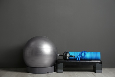 Photo of Set of fitness inventory on floor near grey wall. Space for text