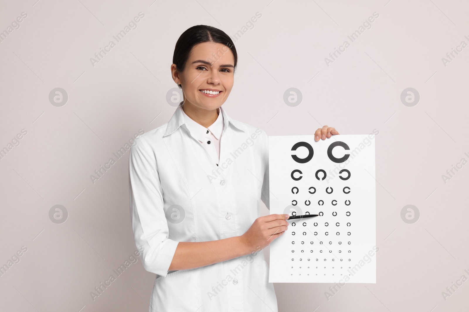 Photo of Ophthalmologist pointing at vision test chart on light background