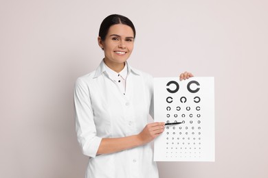 Photo of Ophthalmologist pointing at vision test chart on light background