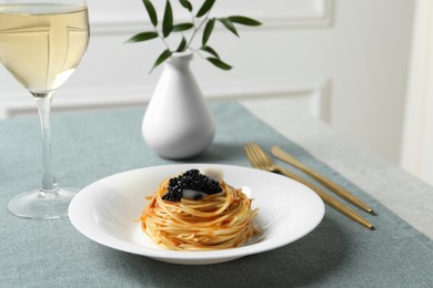 Photo of Tasty spaghetti with tomato sauce and black caviar served on table, closeup. Exquisite presentation of pasta dish