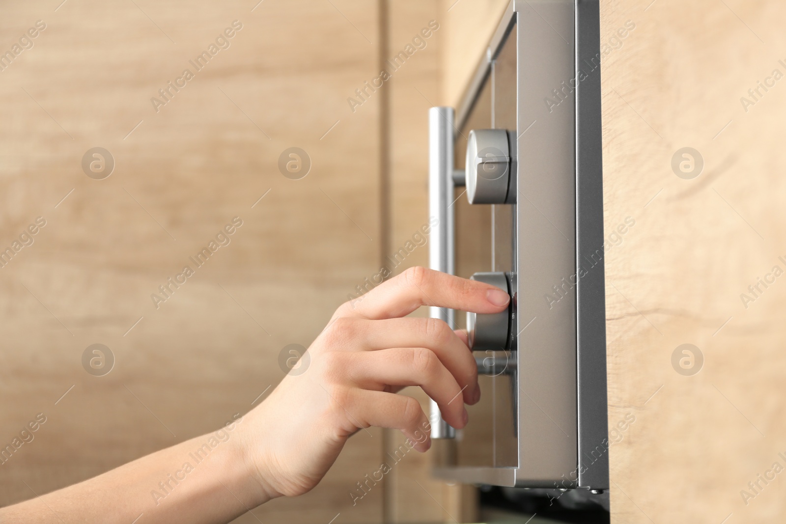 Photo of Young woman adjusting modern microwave oven in kitchen, closeup