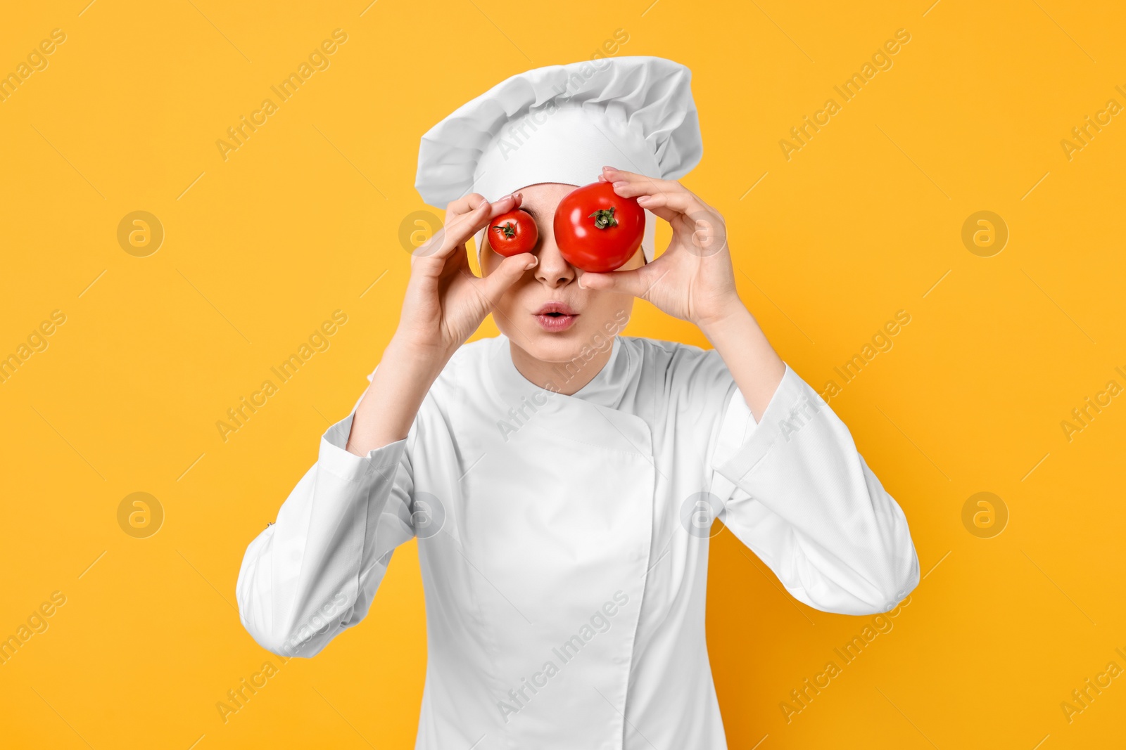 Photo of Professional chef with fresh tomatoes having fun on yellow background