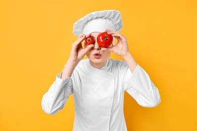 Photo of Professional chef with fresh tomatoes having fun on yellow background