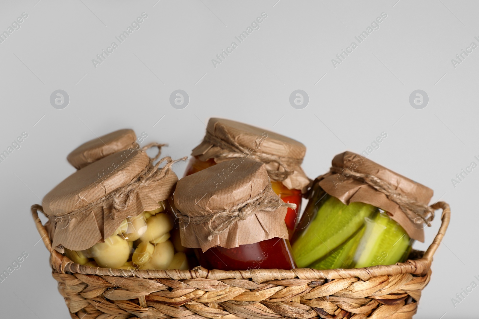 Photo of Wicker basket with many jars of different preserved products