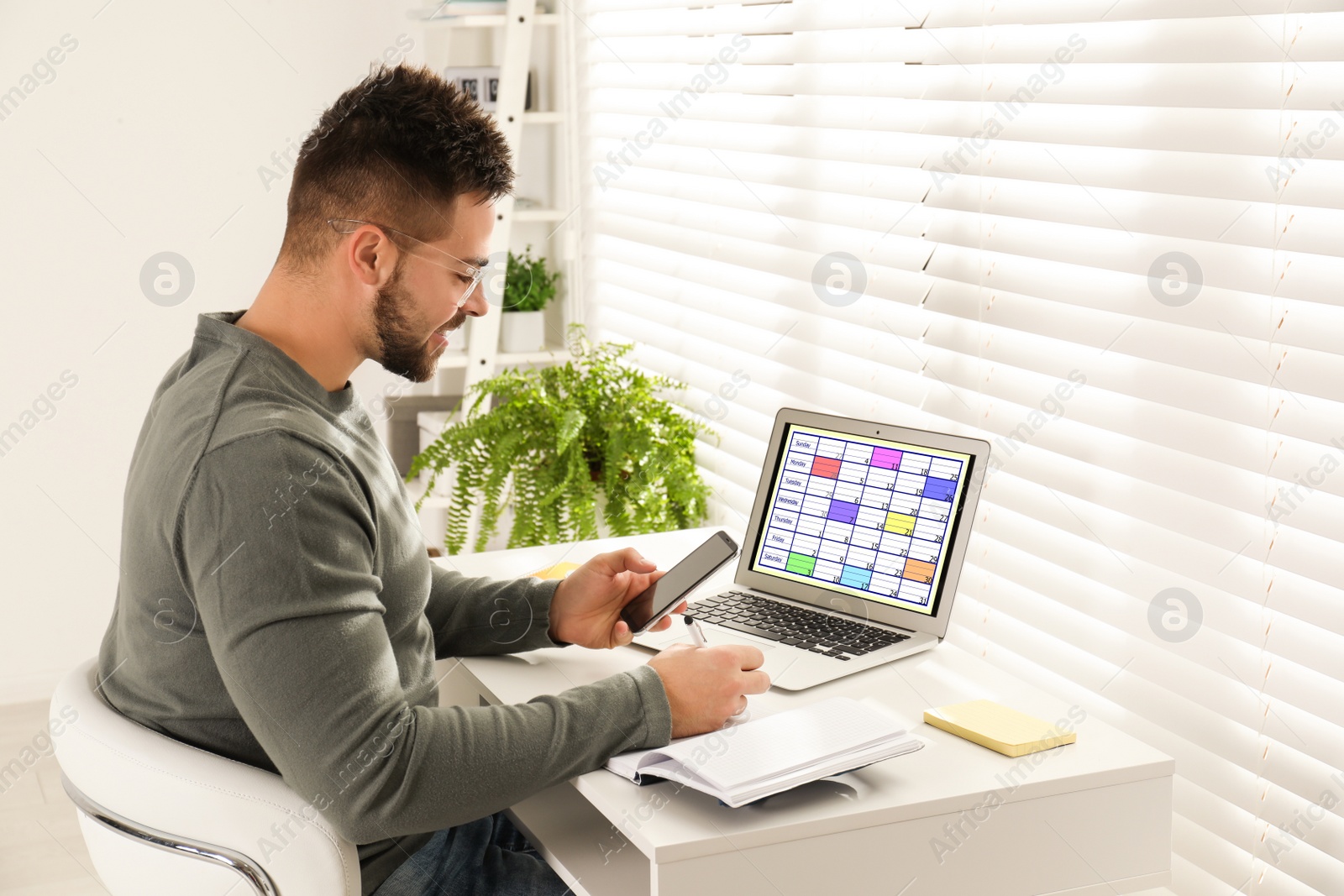 Photo of Young man planning his schedule with calendar app on laptop in office