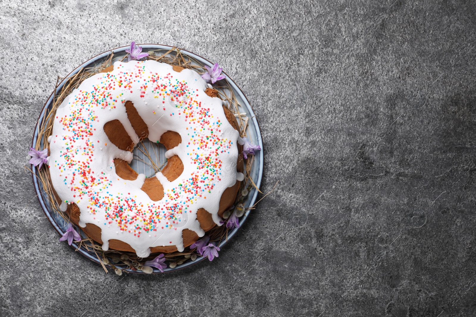 Photo of Glazed Easter cake with sprinkles on grey table, top view. Space for text