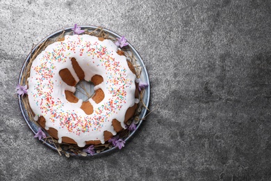 Glazed Easter cake with sprinkles on grey table, top view. Space for text