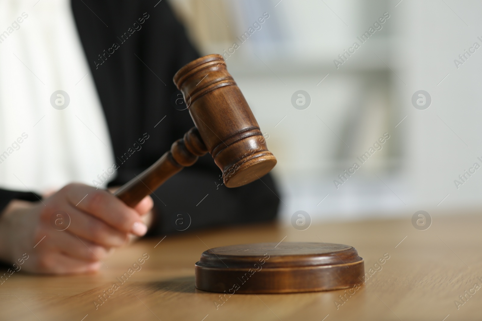 Photo of Judge striking mallet at wooden table in courtroom, closeup. Space for text