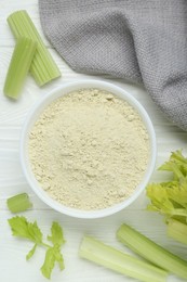 Photo of Natural celery powder in bowl and fresh stalks on white wooden table, flat lay