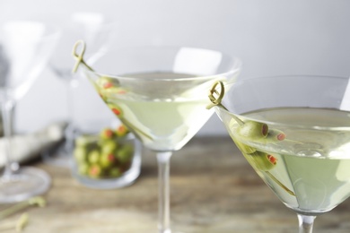 Glasses of Classic Dry Martini with olives on wooden table against grey background, closeup