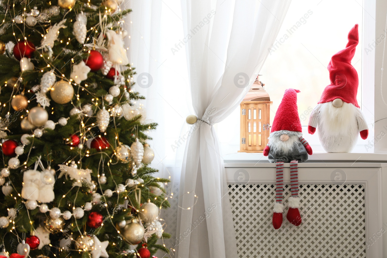 Photo of Cute gnomes near Christmas tree on windowsill in room