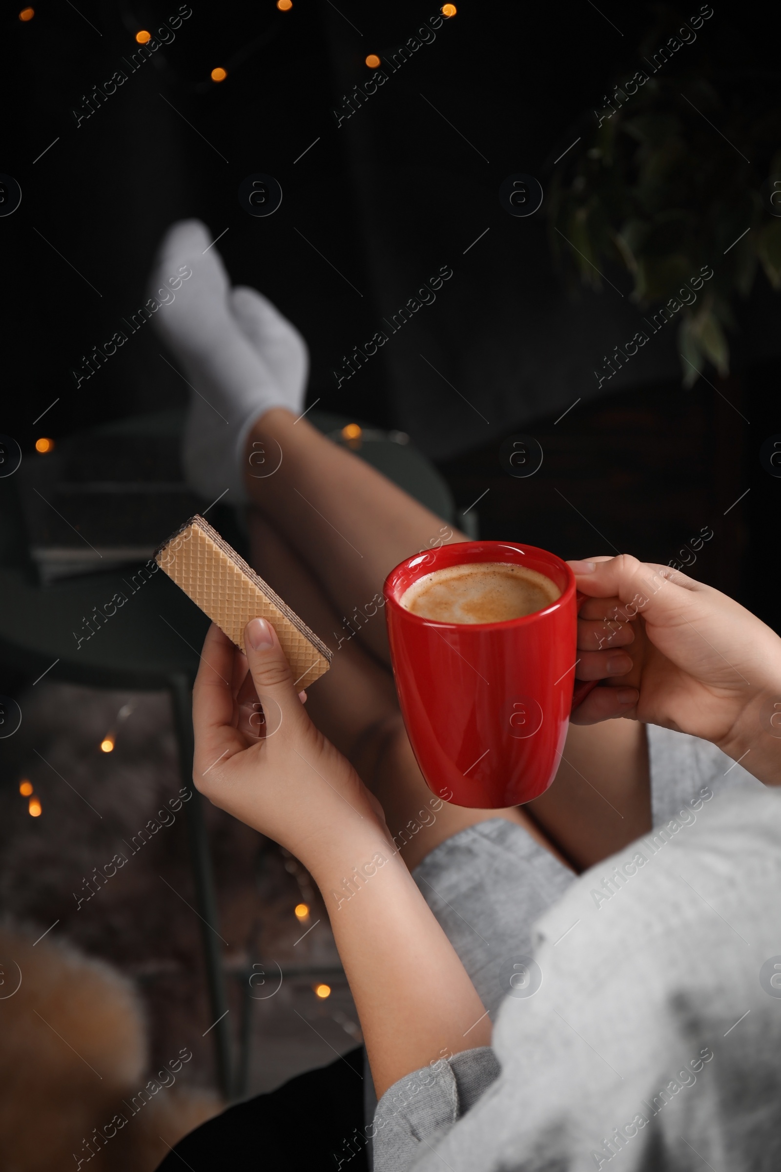 Photo of Woman with wafer and coffee on dark background, closeup. Early breakfast