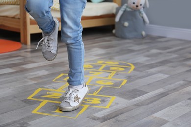 Little girl playing hopscotch at home, closeup