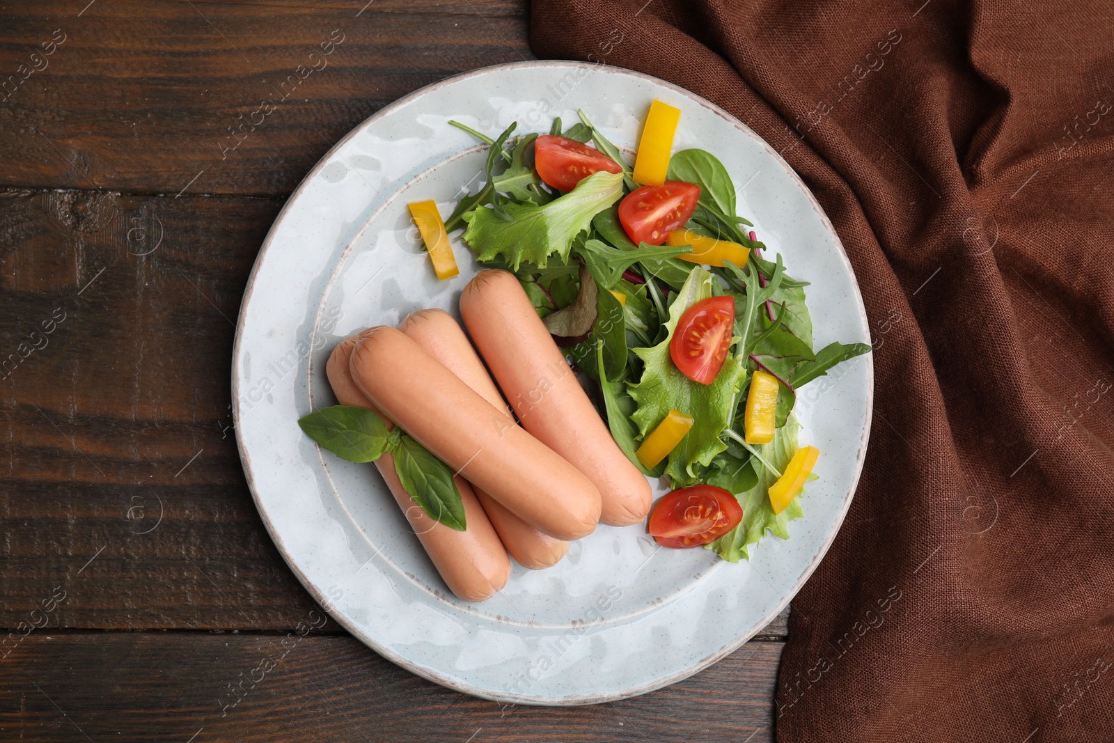 Photo of Delicious boiled sausages with salad on wooden table, top view