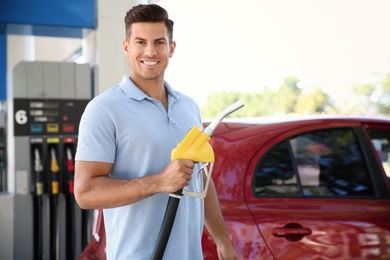 Man with fuel pump nozzle at self service gas station