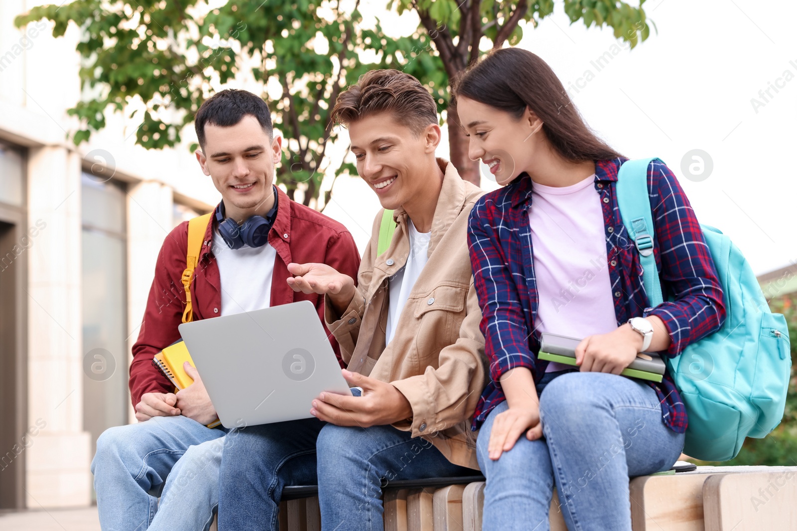 Photo of Happy young students with laptop learning together outdoors