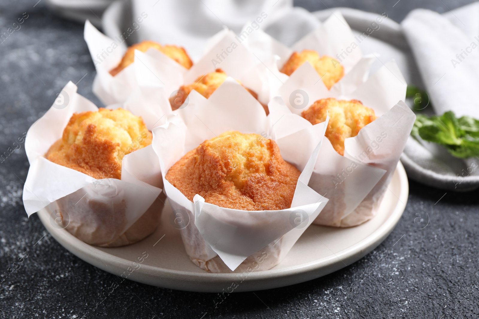 Photo of Delicious sweet muffins on black textured table, closeup