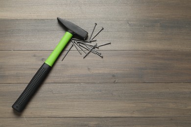 New hammer and metal nails on wooden table, flat lay. Space for text