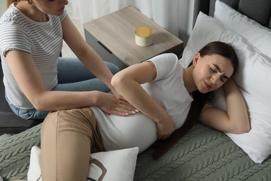 Doula taking care of pregnant woman in bedroom. Preparation for child birth