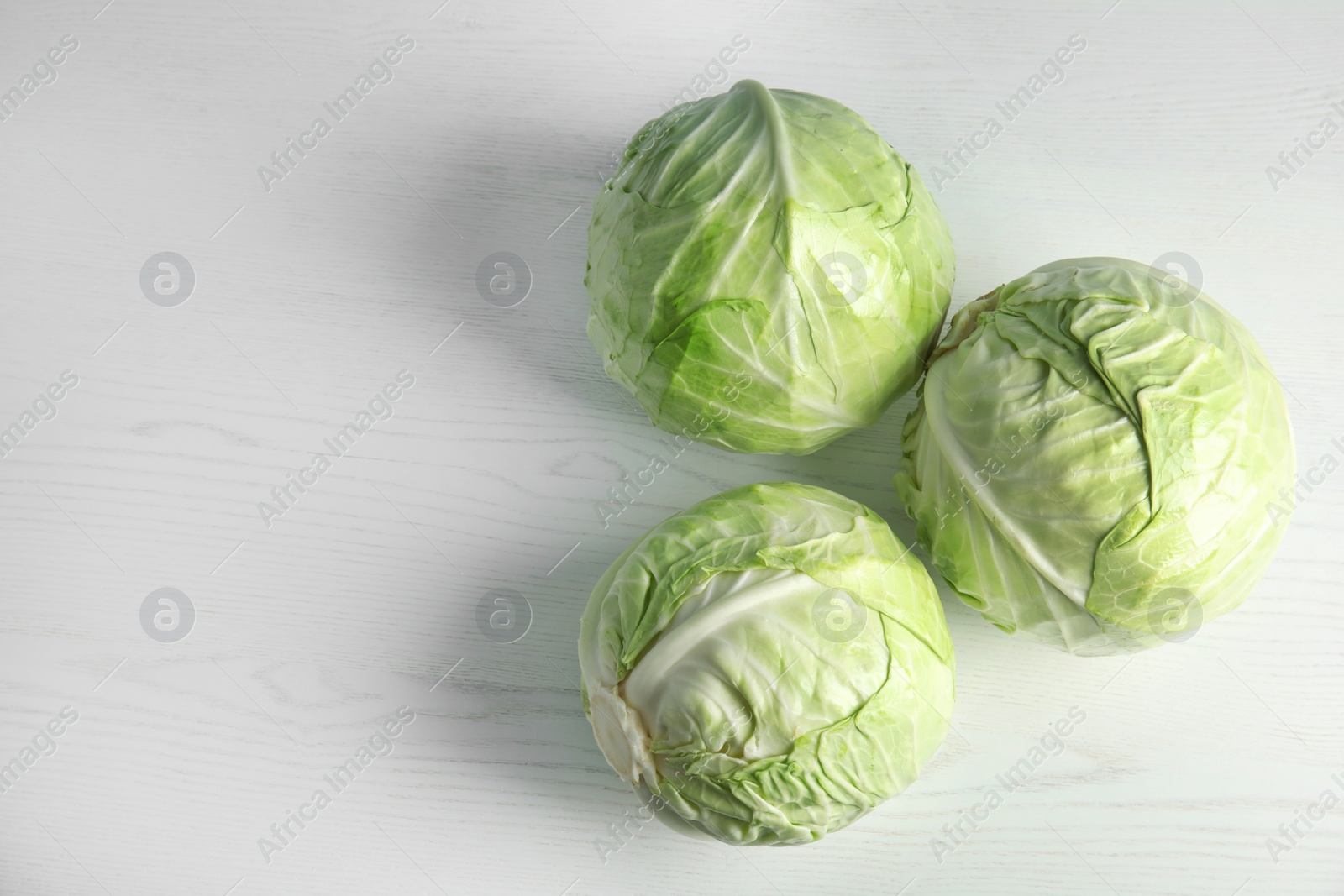 Photo of Whole cabbages on white table. Healthy food