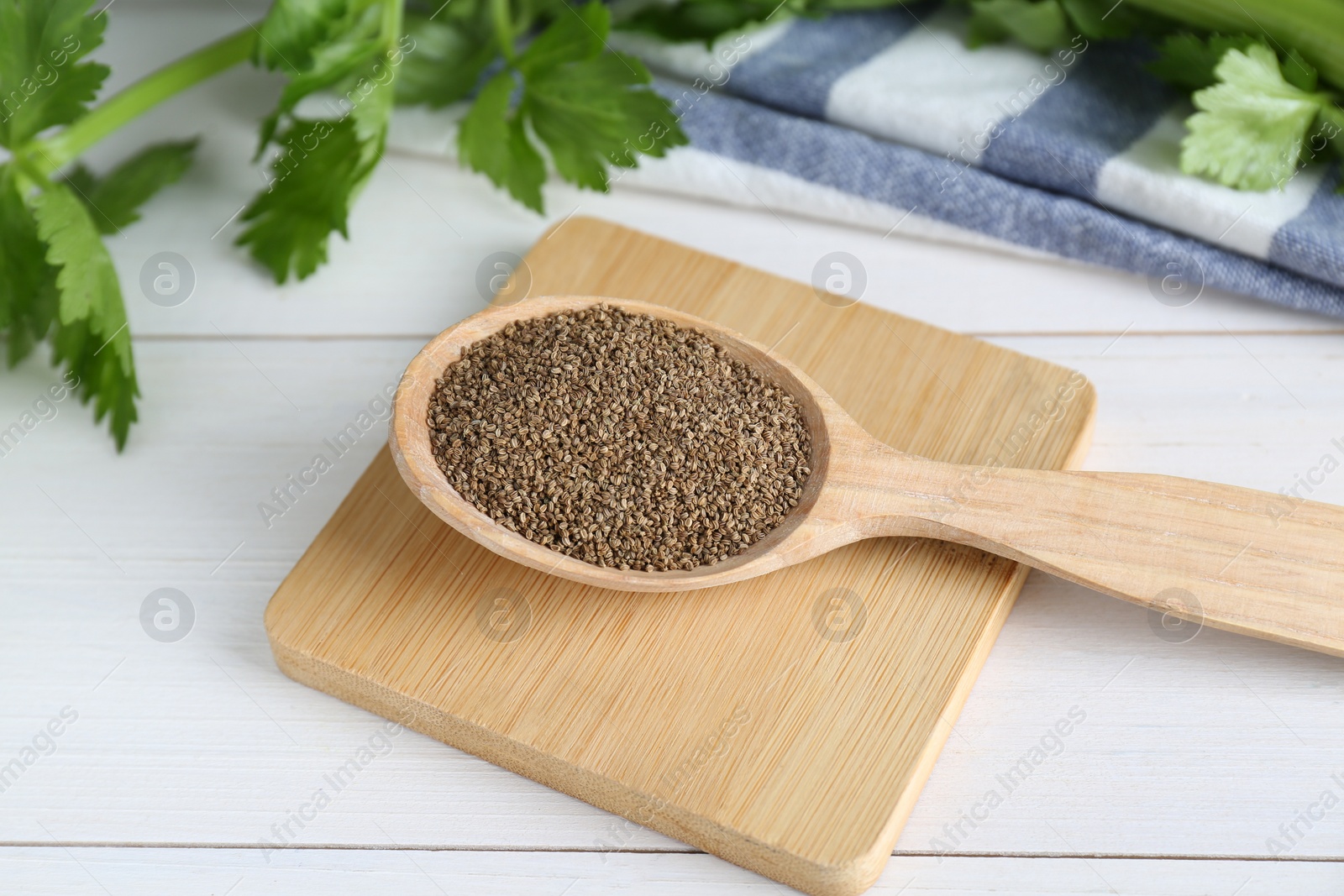 Photo of Spoon of celery seeds on white wooden table