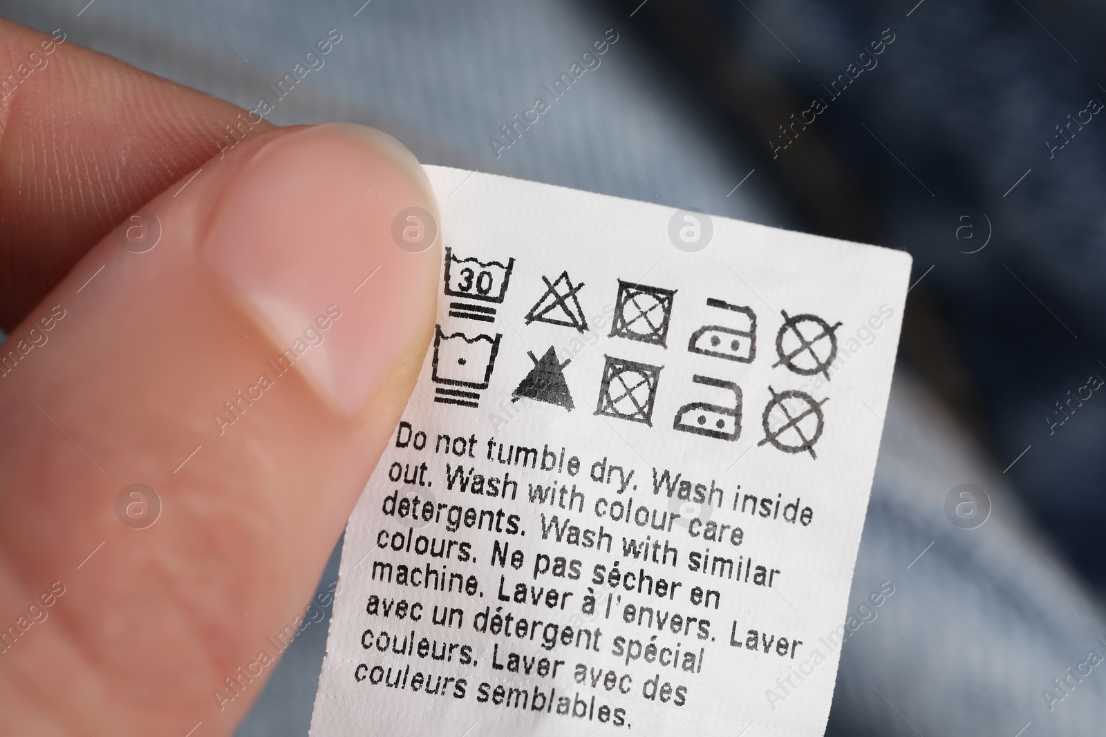 Photo of Woman holding clothing label on blurred background, closeup