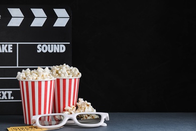 3D glasses, popcorn and clapboard on dark background, space for text