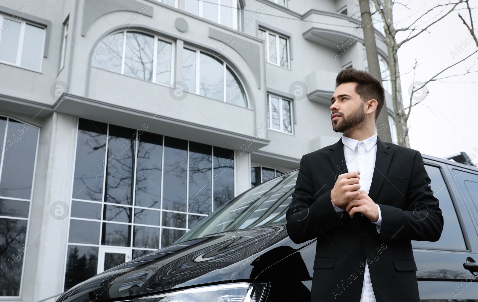 Photo of Handsome young man near modern car outdoors, low angle view