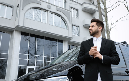 Photo of Handsome young man near modern car outdoors, low angle view