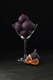 Photo of Tasty raw figs in martini glass on black table