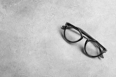 Glasses in stylish frame on light grey background, top view. Space for text