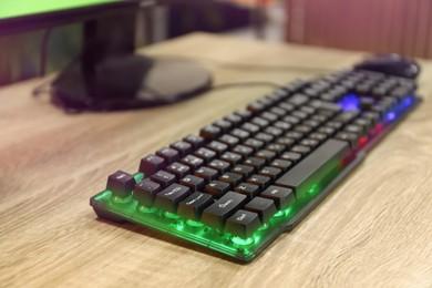 Photo of Modern RGB keyboard on wooden table indoors, closeup