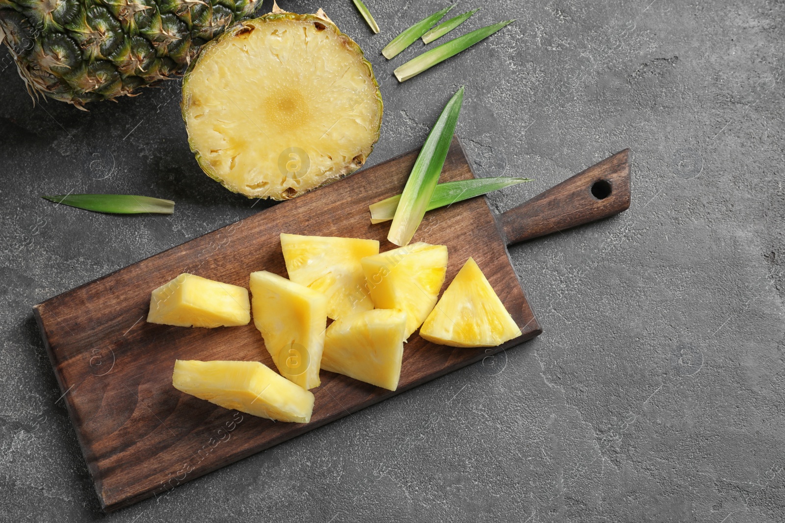 Photo of Wooden board with fresh sliced pineapple on table