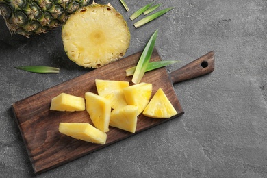 Photo of Wooden board with fresh sliced pineapple on table