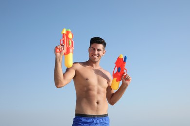 Man with water guns against blue sky