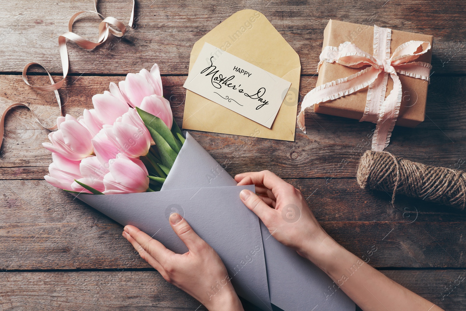 Image of Woman creating beautiful tulip bouquet for Mother's Day at table, top view